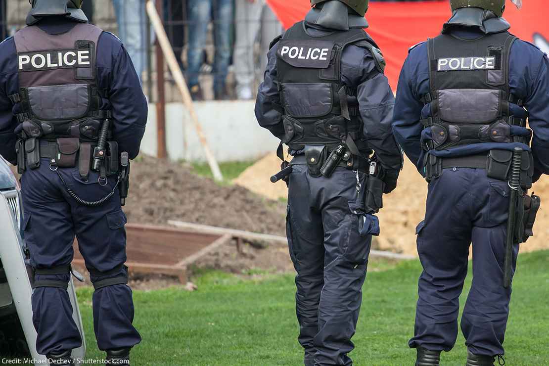 Three police officers in uniform, with "Police" written on the back of their vests.