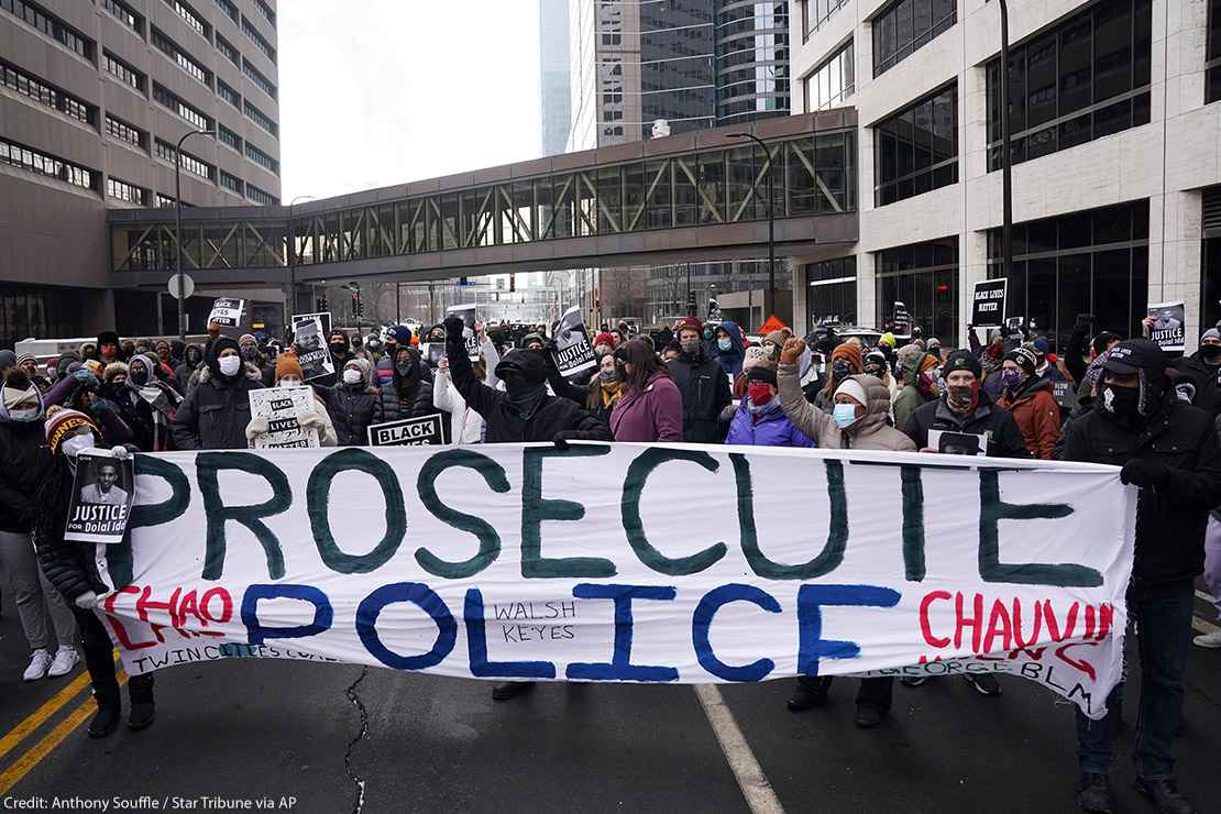 Black Lives Matter protesters stand with a banner that reads "Prosecute Police" to demand justice for Jacob Blake