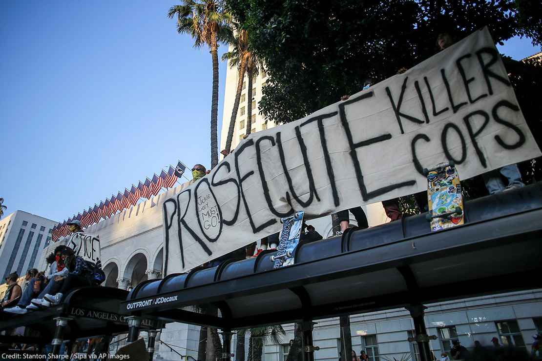 Protesters hold a banner that says, "Prosecute Killer Cops" in front of Los Angeles City Hall during the demonstration.
