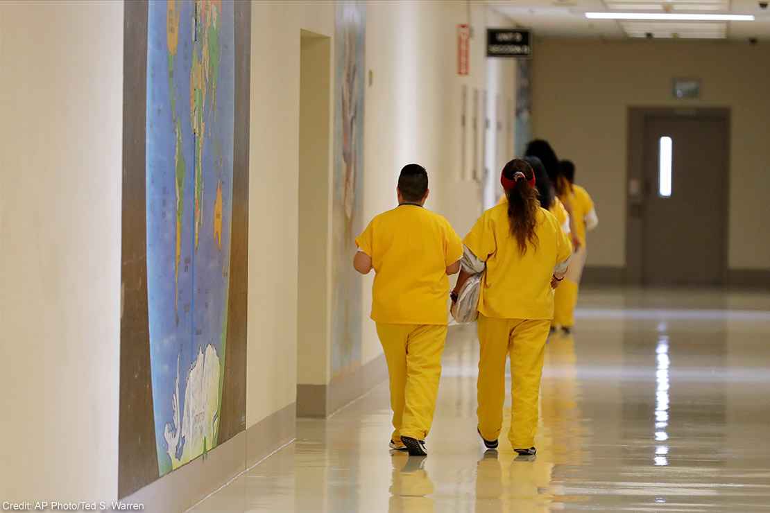 Detainees walk past a map of the world in a hallway of a U.S. Immigration and Customs Enforcement (ICE) detention facility.