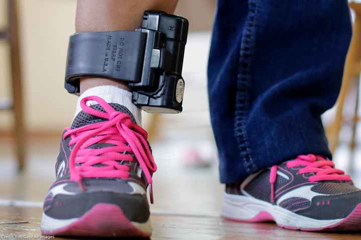 An individual wearing an ankle monitor.
