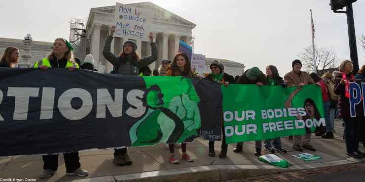 A group of demonstrators holding a banner saying "Our Bodies, Our Freedom."