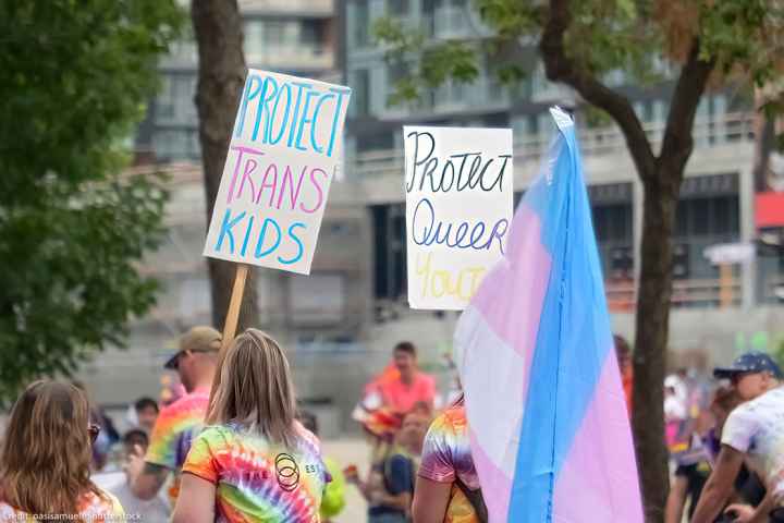 A person holding a sign with the text: Protect Trans Kids, during the pride parade.