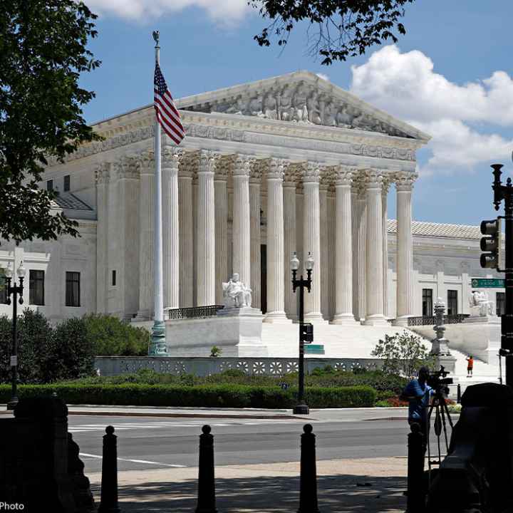 Photo of the American flag on a flag pole and the Supreme Court in Washington, DC.