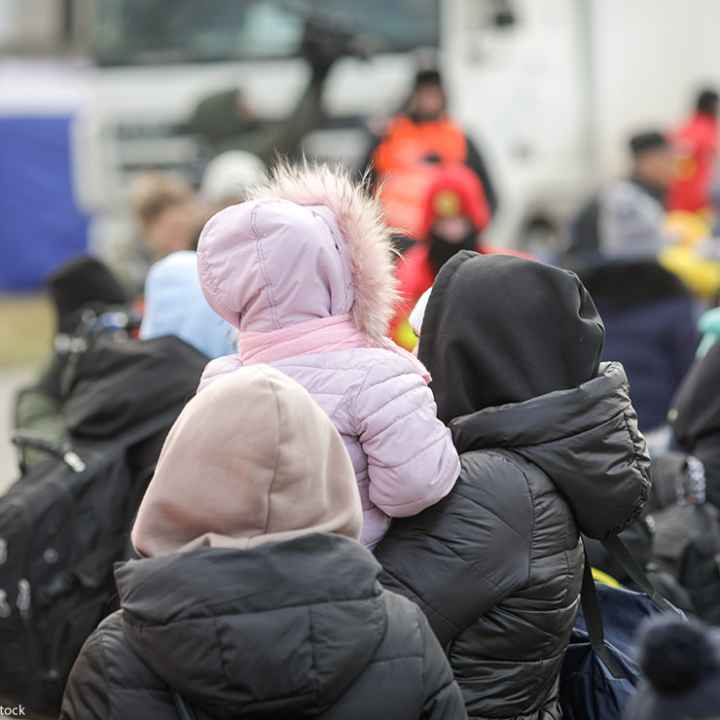 The back of a group of individuals, one holding a child with a hooded coat on.