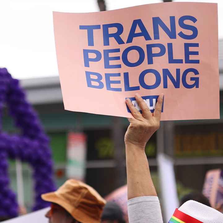 Someone holding a sign saying "Trans People Belong."